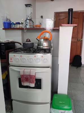 Eine Küche mit Herd, Backofen, Wasserkocher und Mixer auf der Arbeitsfläche.