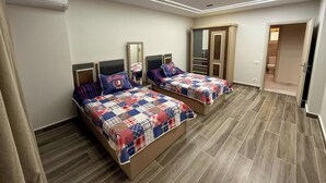 A bedroom with two beds, a wardrobe, and a mirror. - Diarna Latin district Residency (Marsa Matrouh Governorate)