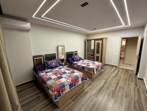 A bedroom with two beds, a wardrobe, and a mirror.