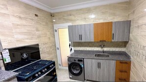 A compact kitchen with a gas stove, washing machine, and a sink. - Diarna Latin district Residency (Marsa Matrouh Governorate)