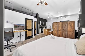 A modern hotel room with a large bed, a desk with a computer, a TV, and a wardrobe. - Urban Luxe Loft in Tampa Heights (Tampa)