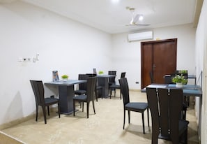 A dining area with tables and chairs, an air conditioning unit, and a ceiling fan.