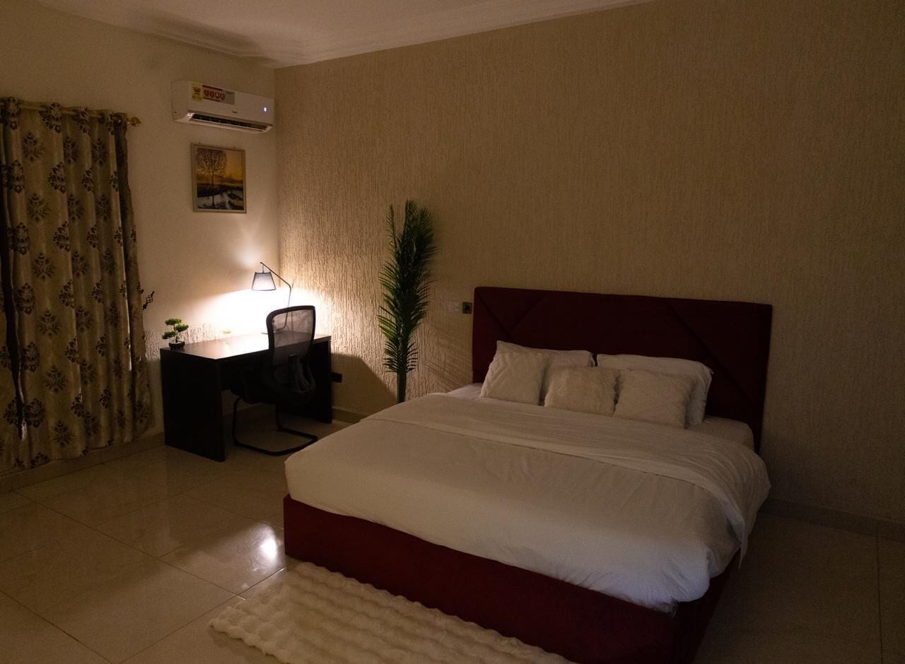 Un dormitorio con cama, escritorio, silla y equipo de aire acondicionado.