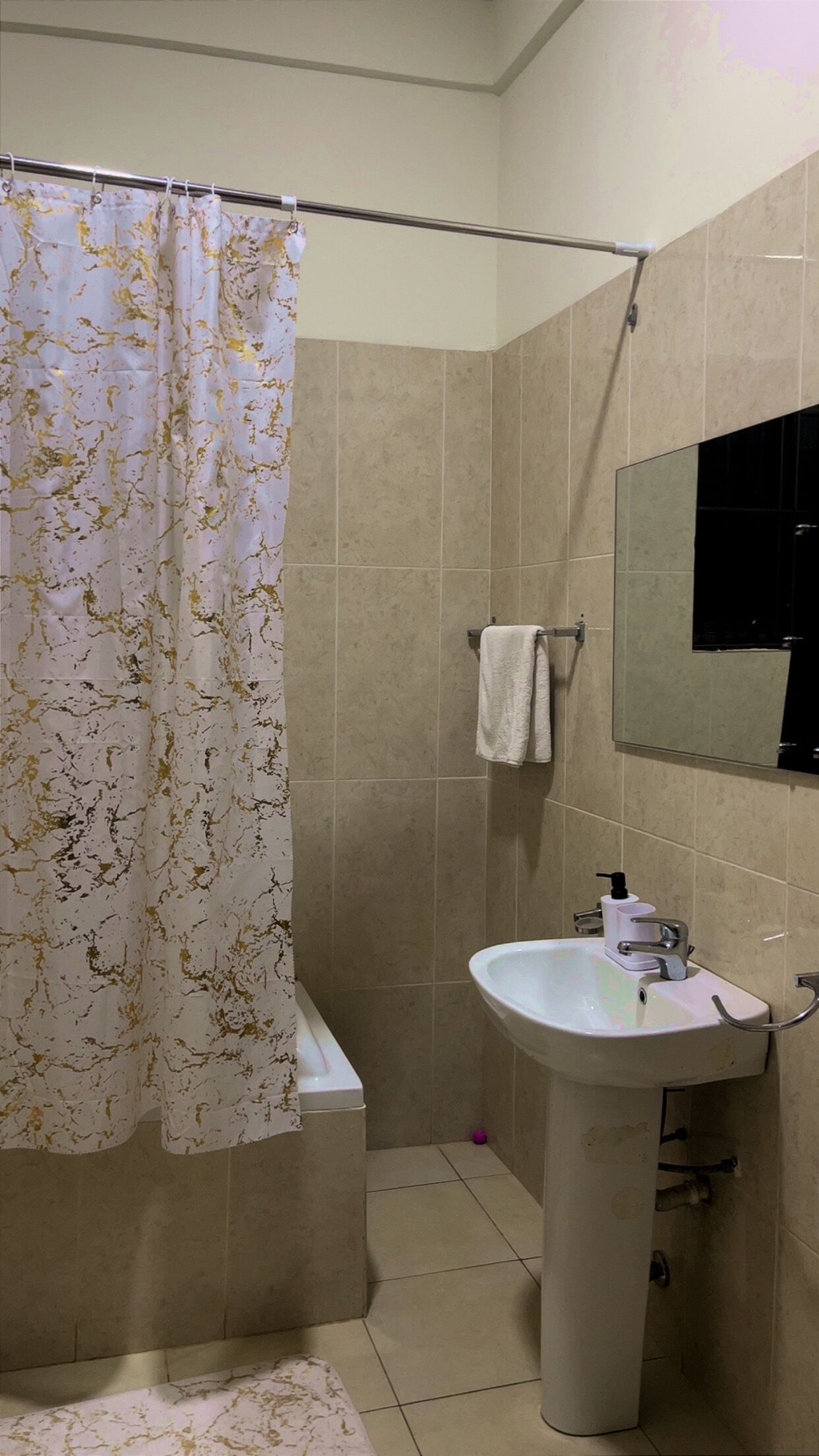 A bathroom with a shower curtain, a sink, a mirror, and a towel rack.