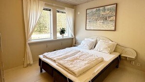 A bedroom with a bed, curtains, a window with a plant, and a painting on the wall. - Cosy Cottage in Dals-Ed, 3 Min Drive from Moose Ranch & Lakes (Ed)