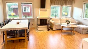 A spacious living room with a fireplace, a dining area, and a sofa. - Cosy Cottage in Dals-Ed, 3 Min Drive from Moose Ranch & Lakes (Ed)