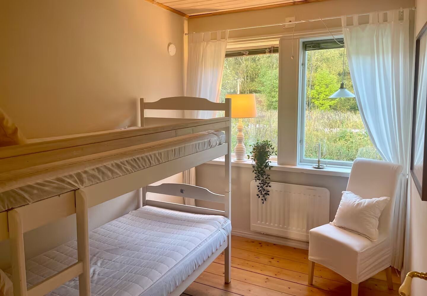 Une chambre avec un lit superposé, une fenêtre, une chaise et une lampe.