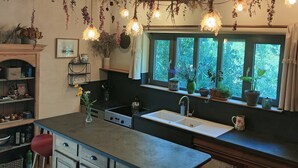Et køkken med en central ø, barstole, en komfur og et vindue med planter.