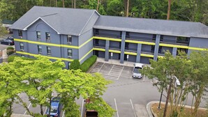 Un immeuble à plusieurs étages doté d’un parking, entouré d’arbres.