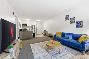 Ein modernes Wohnzimmer mit einem blauen Sofa, einem Holztisch und einem Fernseher.