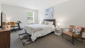 Une chambre d’hôtel moderne équipée d’un lit, d’un bureau, d’une chaise et d’une grande fenêtre.