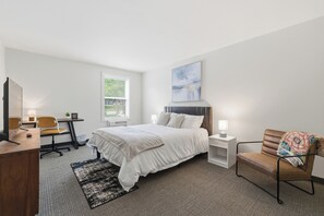 Ein modernes Hotelzimmer mit Bett, Schreibtisch, Stuhl und einem großen Fenster.