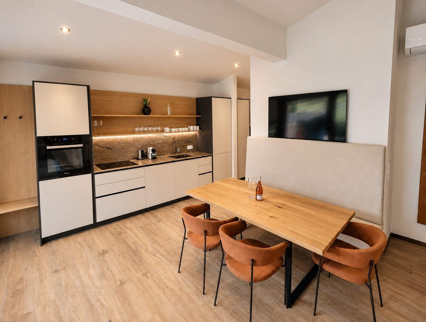 A modern kitchen with a wooden countertop, built-in oven, and a dining area with a wooden table and four chairs.