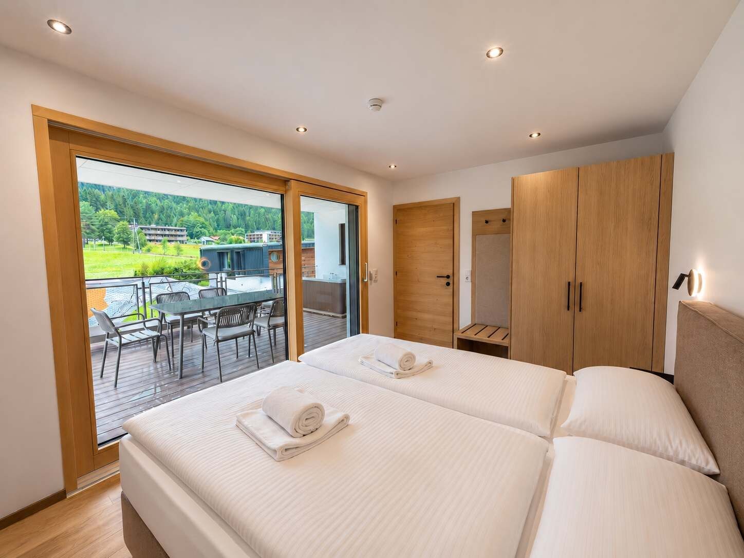 Een slaapkamer met een groot bed, een houten kledingkast en een balkon met een tafel en stoelen.