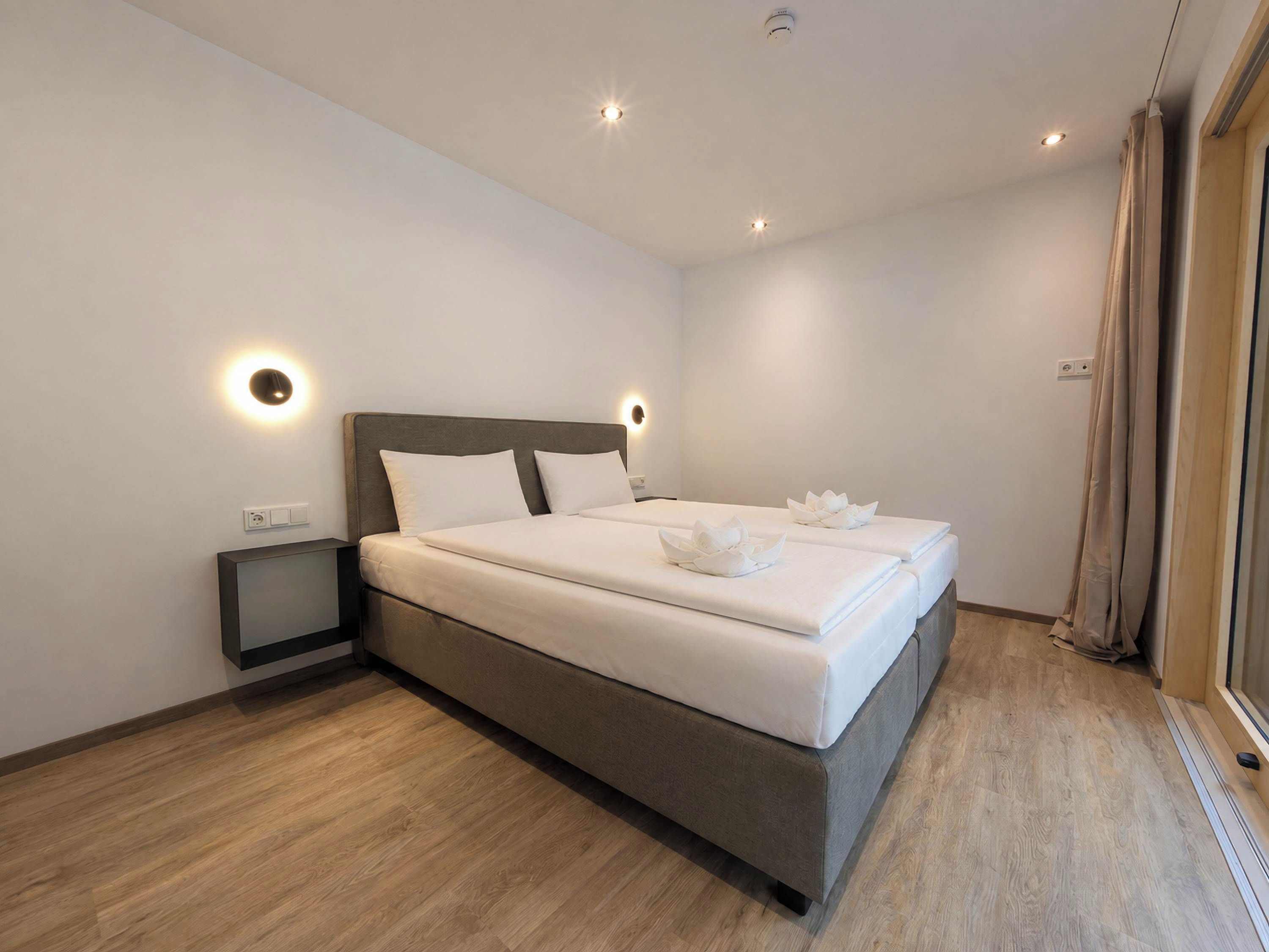 Une chambre moderne avec un grand lit, des tables de chevet et un luminaire au plafond.