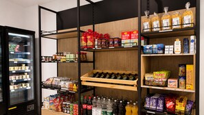 Un supermercado con estantes llenos de diversos productos alimenticios, una sección refrigerada y una exhibición de bebidas embotelladas.