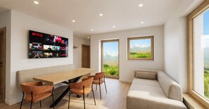 A modern living room with a wooden dining table, orange chairs, a beige sofa, and a large TV displaying Netflix content. - BASE Achensee Soul No7 – Private hot tub (Achenkirch)
