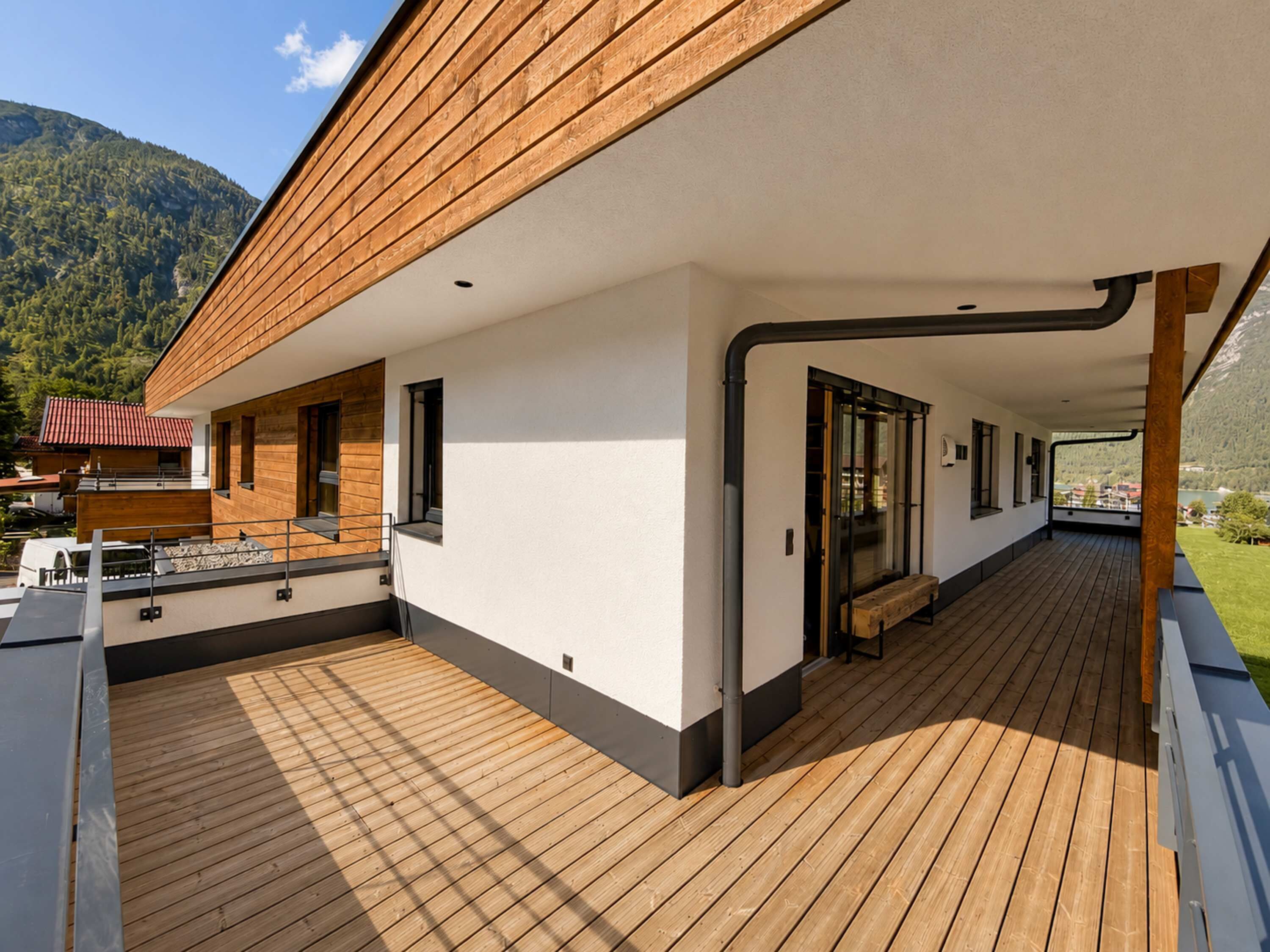 Ein modernes Gebäude mit einer Holzdielung, großen Fenstern und Blick auf Berge.