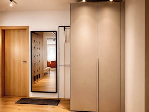 A hallway with a wooden door, a mirror, and a wardrobe.