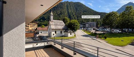 A balcony with a view of a town center, including a church and a parking area.