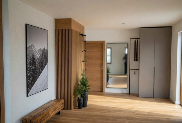 A hallway with a wooden bench, a large framed picture, a tall wooden panel, a mirror, and a wardrobe.