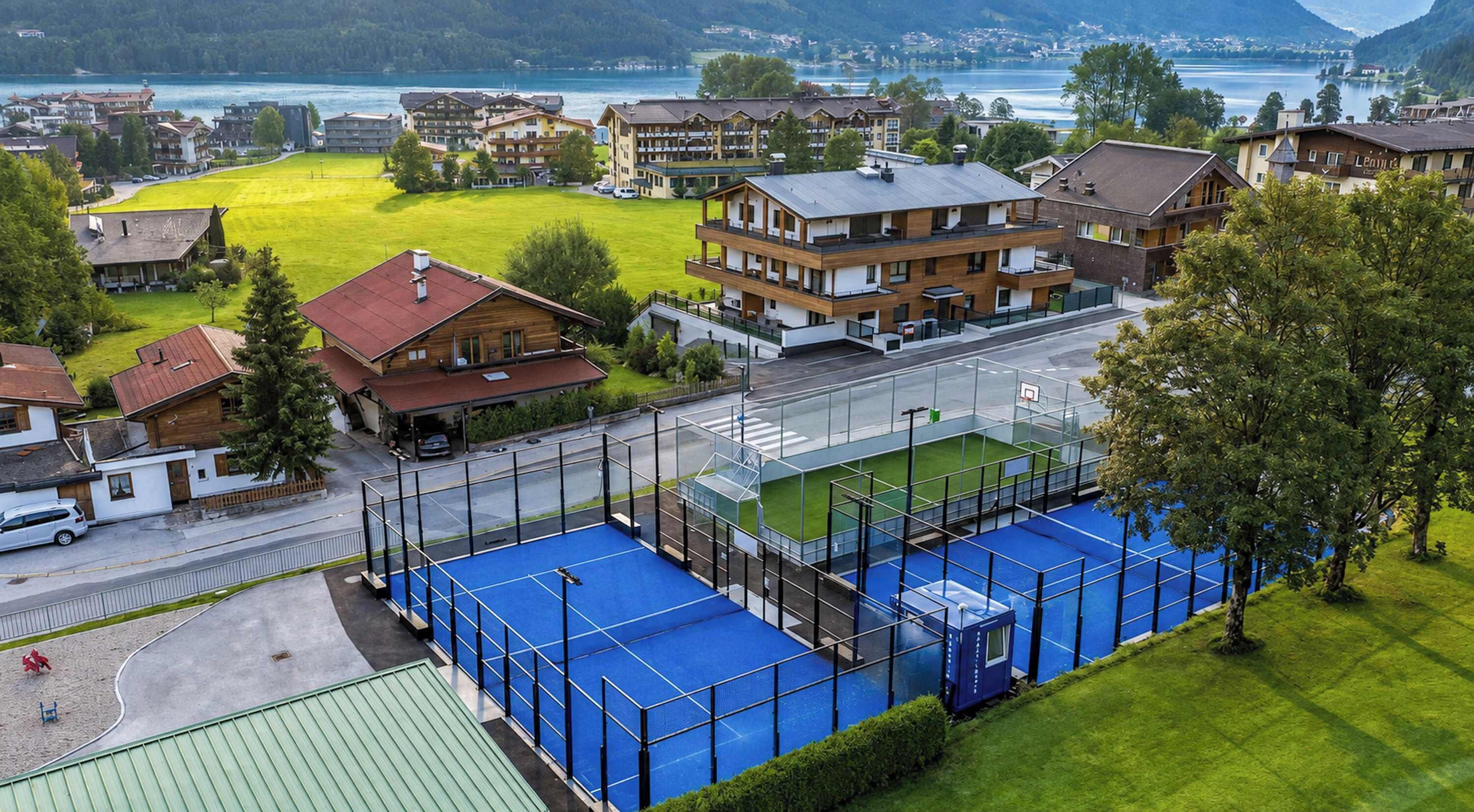 Ein Wohngebiet mit Sportplatz, Häusern und einem See im Hintergrund.