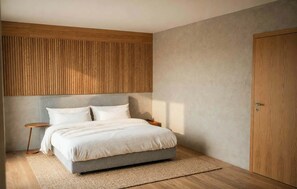 A bedroom with a bed, wooden headboard, bedside table, and a wardrobe.