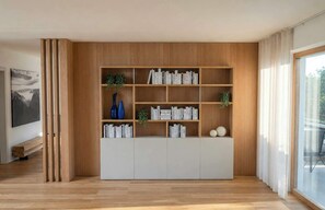 Una sala moderna con una estantería de madera, un banco y un ventanal grande.
