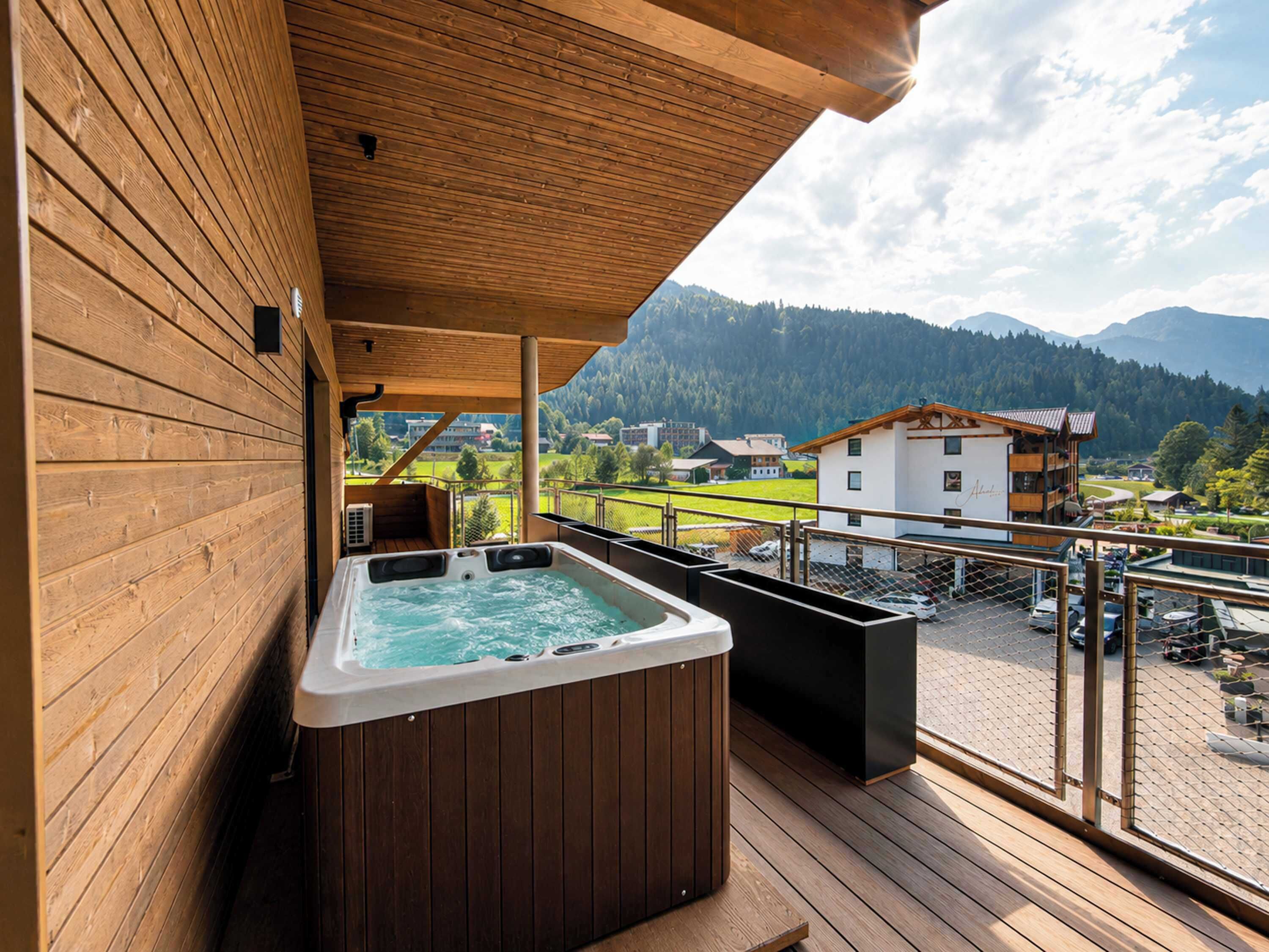 A wooden deck with a hot tub and a view of a mountainous landscape.