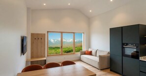 Eine moderne Küche mit großem Fenster, einer Couch und einem Esstisch.
