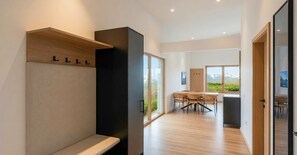 Ein modernes Interieur mit einer Holzbank, einer schwarzen Säule und einem Essbereich mit Korbstühlen.