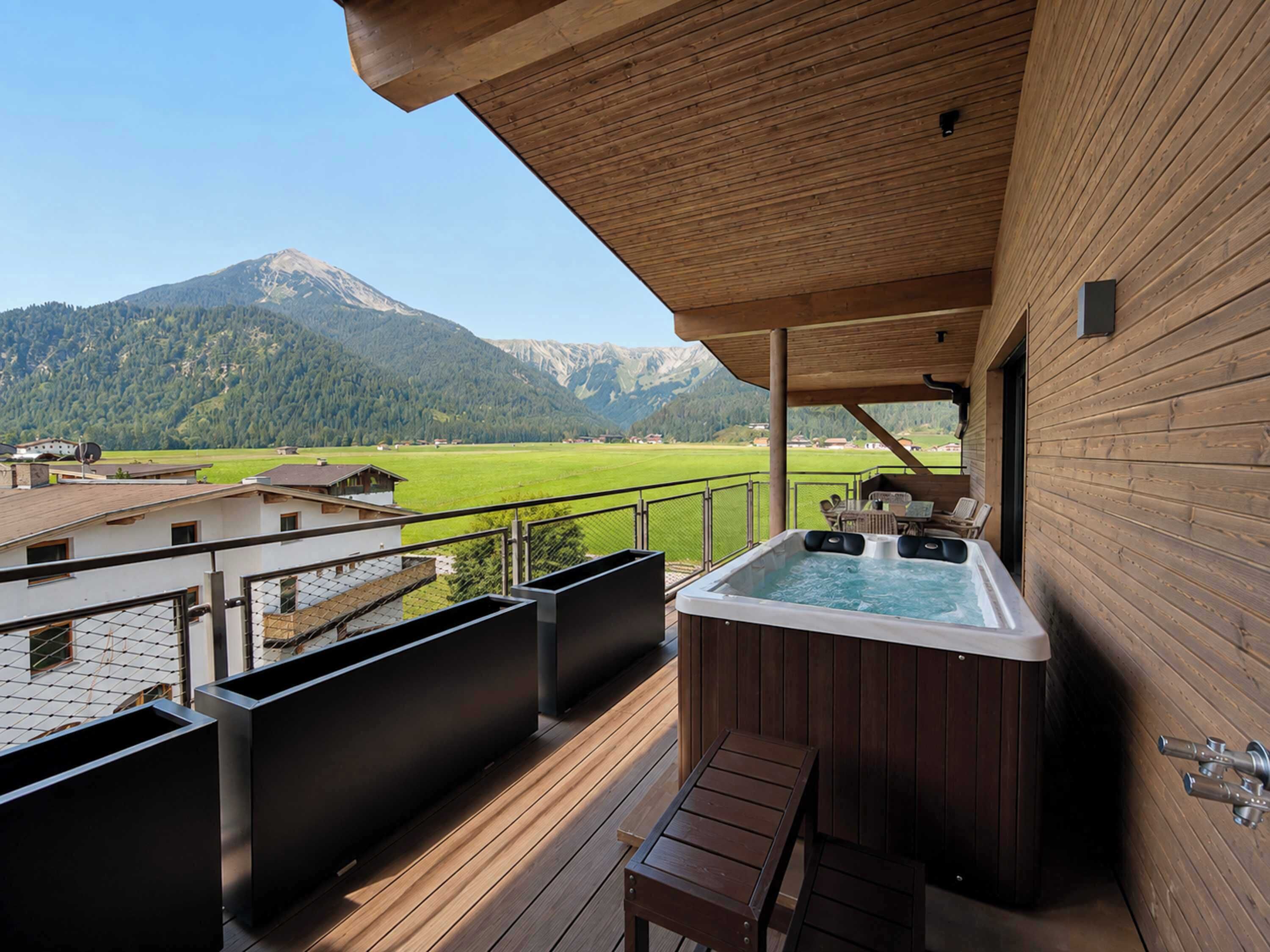 A hot tub on a wooden deck with a mountain view.