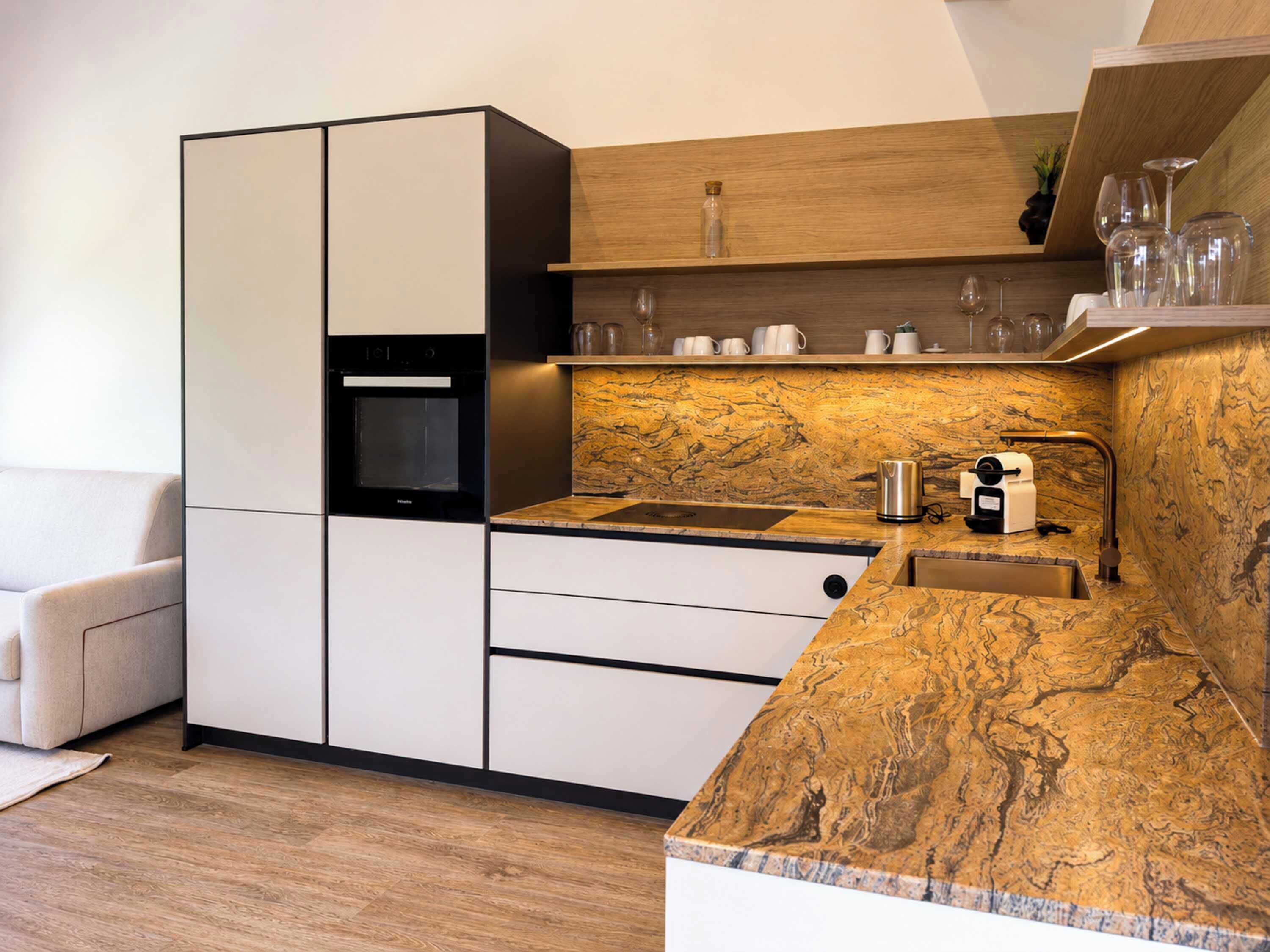 Eine moderne Küche mit Einbauofen, Mikrowelle und einer Arbeitsplatte aus Marmor.