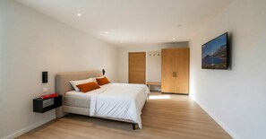 Ein modernes Schlafzimmer mit einem Bett, einem Nachttisch, einem Kleiderschrank und einem Bild an der Wand.