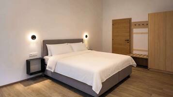 A modern bedroom with a large bed, bedside tables, a wardrobe, and built-in lighting.