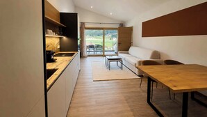 Een moderne keuken met een eethoek, een bank en uitzicht op een groen landschap.