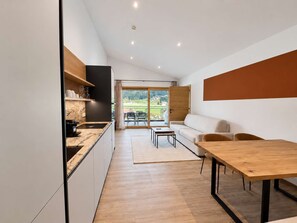 Eine moderne Küche mit Backofen und einer Essecke mit Holztisch und Stühlen.