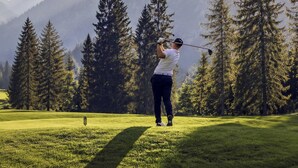 A person playing golf on a course with a backdrop of tall trees and mountains. - BASE Achensee Soul N°32 (Achenkirch)