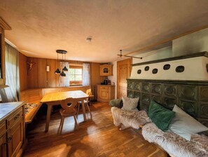 Un interior de cabaña acogedor con paredes de madera, una mesa de comedor, un sofá y un cabecero grande.