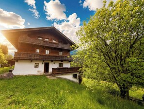 A two-story wooden chalet with a balcony, surrounded by lush greenery and a clear sky. - CHALET Naschberg - 5 BR, Terrace & Mountain View (Scheffach)