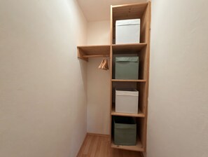 Ein Holzkleiderschrank mit mehreren Regalen und Kleiderstange.