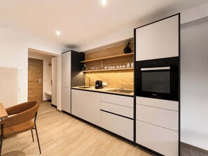Een moderne keuken met een ingebouwde oven, een koffieapparaat en een houten aanrecht.