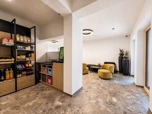 Ein modernes Interieur mit Empfangsbereich, Sitzgelegenheiten und einem Selbstbedienungsterminal.