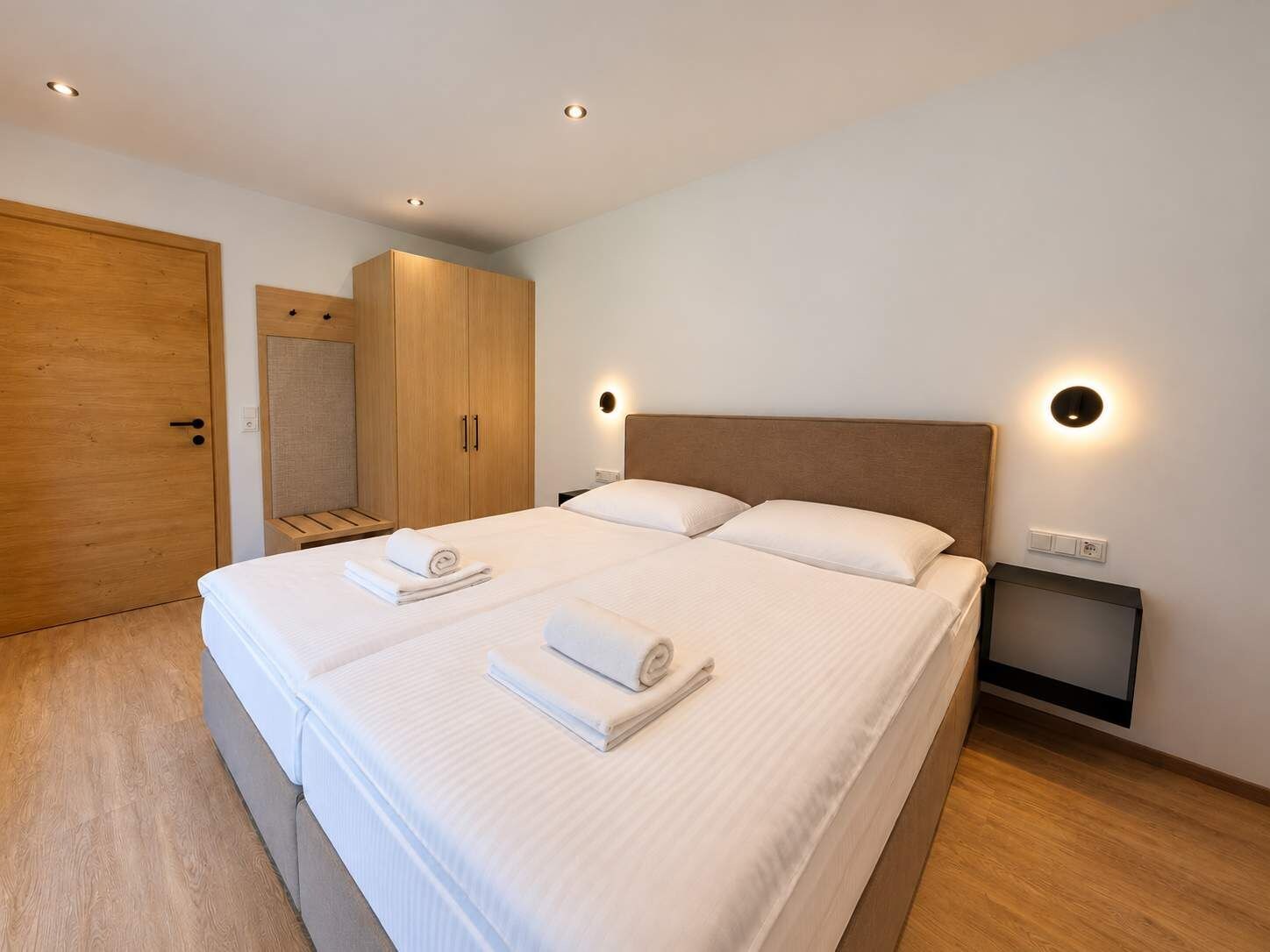 Ein Hotelzimmer mit Doppelbett, Holzschrank und einem kleinen Nachttisch.