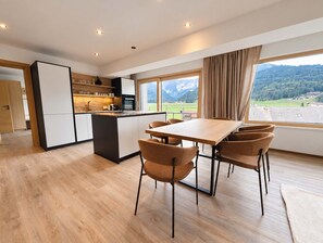 Cozinha moderna com área de jantar, piso de madeira e vista para uma paisagem montanhosa.