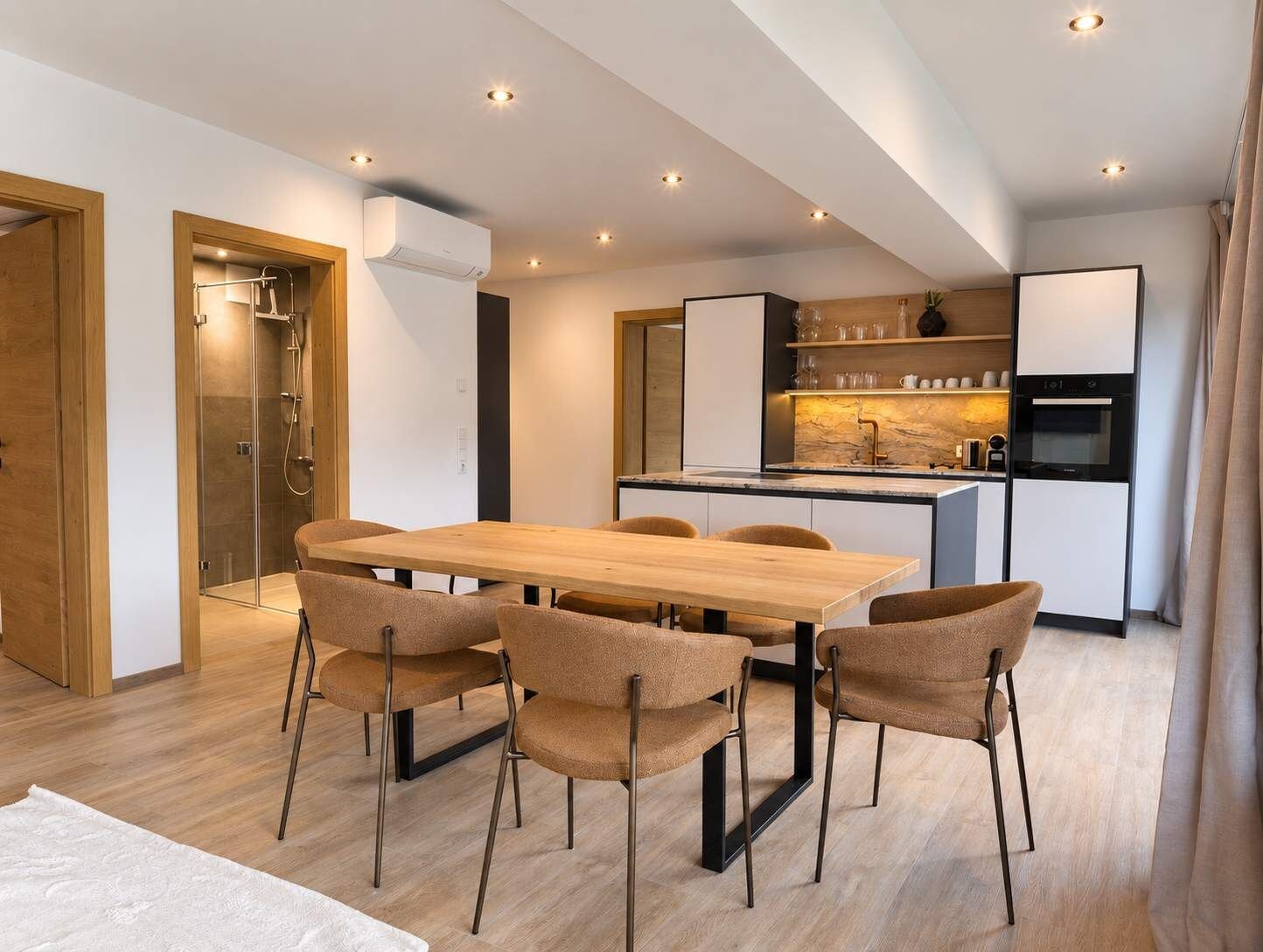 Eine moderne Küche mit Kochinsel, integrierten Geräten und einem Essbereich mit Holztisch und Stühlen.