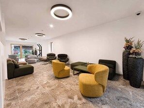 A modern living room with a fireplace, multiple seating options, and a view of the outdoors. - BASE Achensee Energy N°25 – Terrace (Achenkirch)