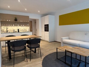 A modern living space with a dining area, kitchen, and seating area. - BASE Achensee Energy N°25 – Terrace with a daybed (Achenkirch)