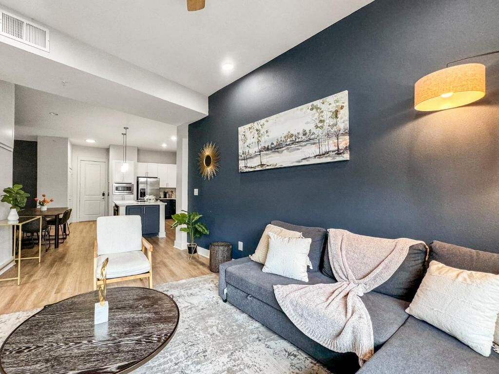 Una sala de estar moderna con un sofá gris, una mesa de centro y un cuadro en la pared.