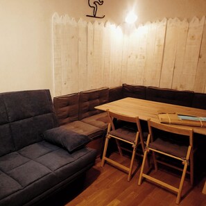 A corner room with a dark-colored sofa, a wooden table, and a white curtain.